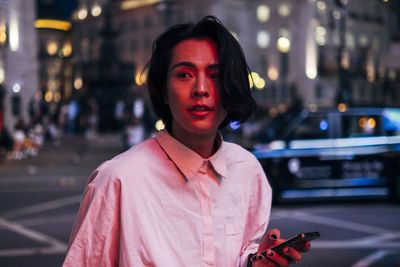 Portrait of man standing on street in city at night