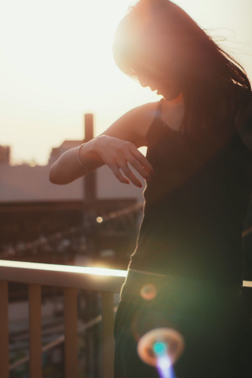 one person, railing, leisure activity, real people, outdoors, sunset, standing, women, sky, clear sky, young women, day, nature, young adult, close-up, human hand, people