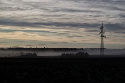 Electricity pylon on field against sky during sunset