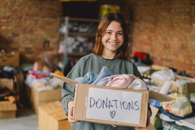 Volunteer teengirl preparing donation boxes for people.