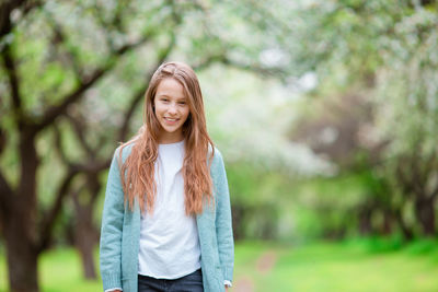 Portrait of smiling girl sanding against trees