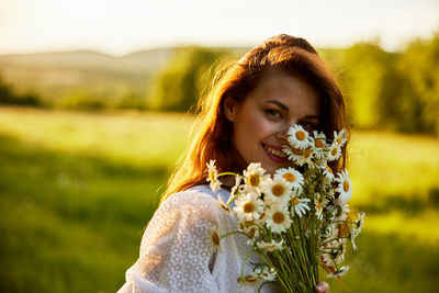 Portrait of smiling young woman blowing flowers