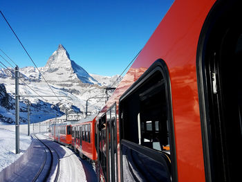 Train on snow covered mountain against blue sky, mt matherhorn switzerland