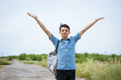 Happy young man posing with raised arms, standing