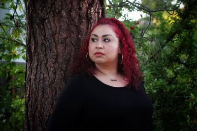 Portrait of woman against tree trunk