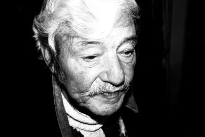 Close-up portrait of mid adult man against black background