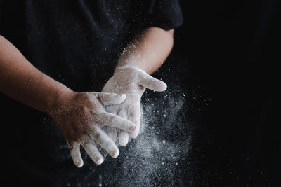 Close-up of hand holding crystal against black background