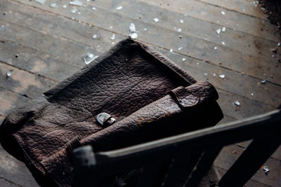 High angle view of weathered leather bag on chair
