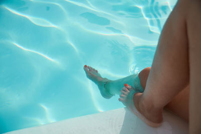 Low section of woman relaxing in swimming pool