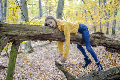 Girl sleeping on tree trunk in forest