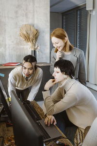 Smiling businesswoman with programmers looking at computer in startup office