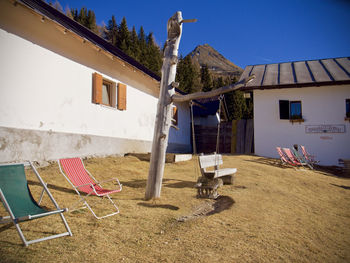 Chairs and tables outside house on field against sky