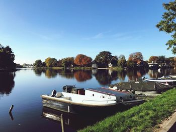 Boats in lake against clear blue sky