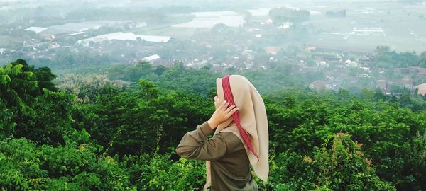 Midsection of woman standing by plants against trees