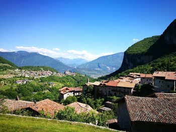 Houses by mountains against clear blue sky