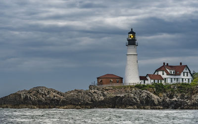 Lighthouse by sea against sky