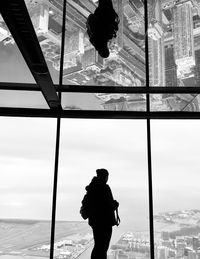 Man looking through window against sky