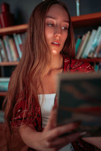 Young woman reading book at library