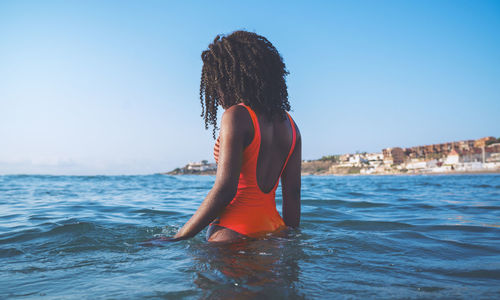 Midsection of woman against sea against clear sky