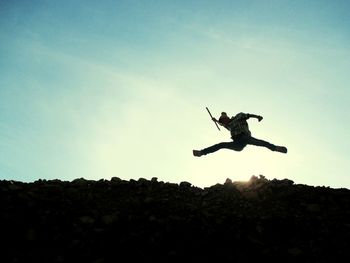Low angle view of person jumping against clear sky