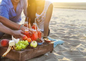 Friends drinking juice on beach