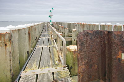 View of wooden fence by sea against sky