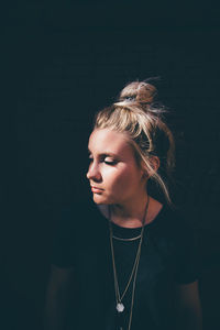 Young woman looking away over black background