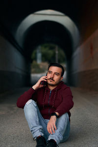 Young man looking away while sitting outdoors