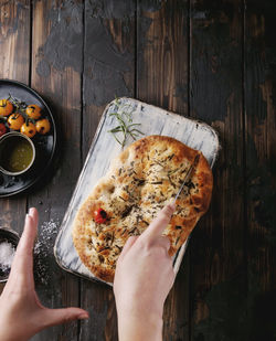 High angle view of hand holding pizza on table