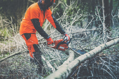 Man holding a chainsaw and cut trees. lumberjack at work. gardener working in the forest. 