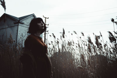 Side view of woman looking away on field against sky