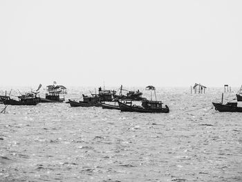 Boats sailing in sea against clear sky