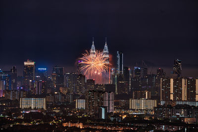 Firework display over illuminated buildings in city at night