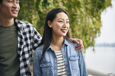 Young couple looking away while standing outdoors