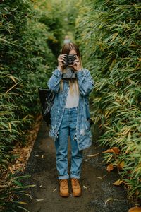 Full length of woman photographing in amidst tree