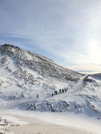 People on snowcapped mountain against sky