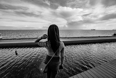 Rear view of woman photographing sea against sky