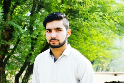 Close-up portrait of young man standing against trees