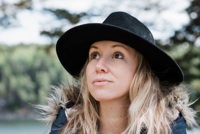 Portrait of a woman with a hat on looking up to the sky thinking