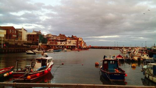 Boats moored in sea by town against sky