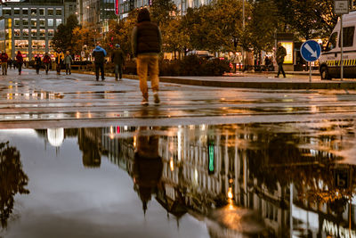 People walking on illuminated city by water