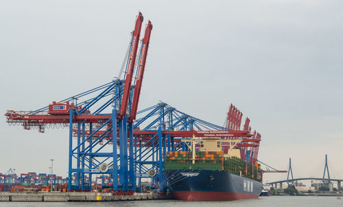 Cranes at pier against sky