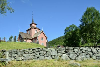 Stone wall by building against clear blue sky