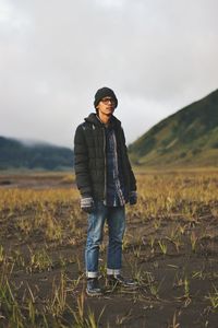 Full length portrait of young man standing on field