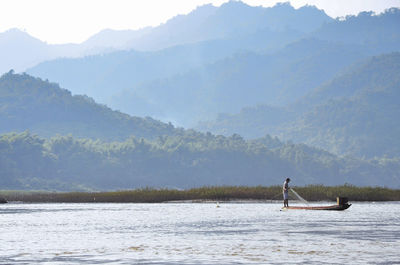 Man surfing on lake against clear sky