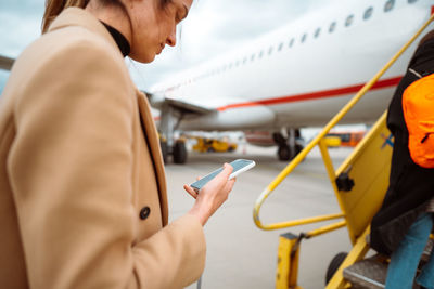 Young woman holding a mobile phone and writing message. boarding to the aircraft. journey