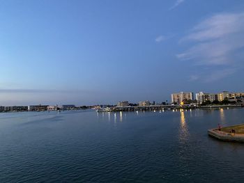 Sea by buildings against blue sky