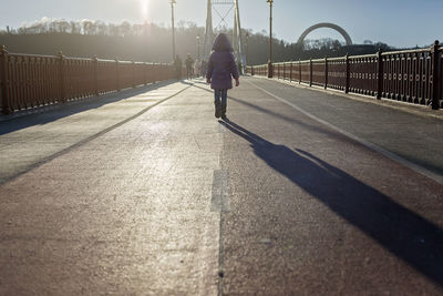 Rear view of man walking on bridge