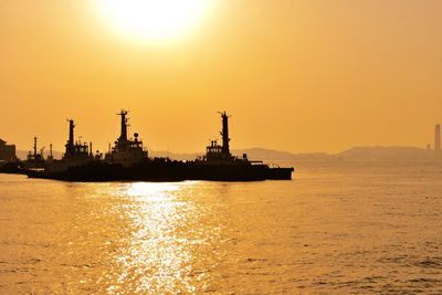 Ships sailing in sea against clear sky during sunset