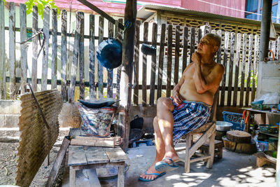 Full length of shirtless man sitting outdoors